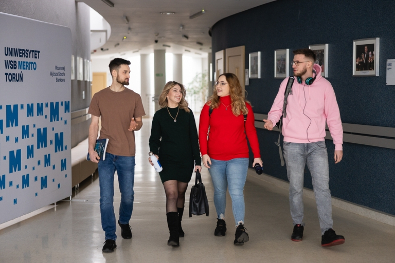 Student Council | WSB Merito Toruń University: Grupa czterech studentów idzie korytarzem uniwersytetu WSB Merito w Toruniu