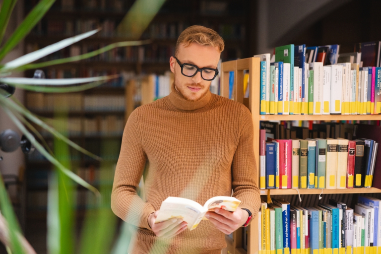Academic publications | WSB Merito Toruń University: A male student in a library reading a book