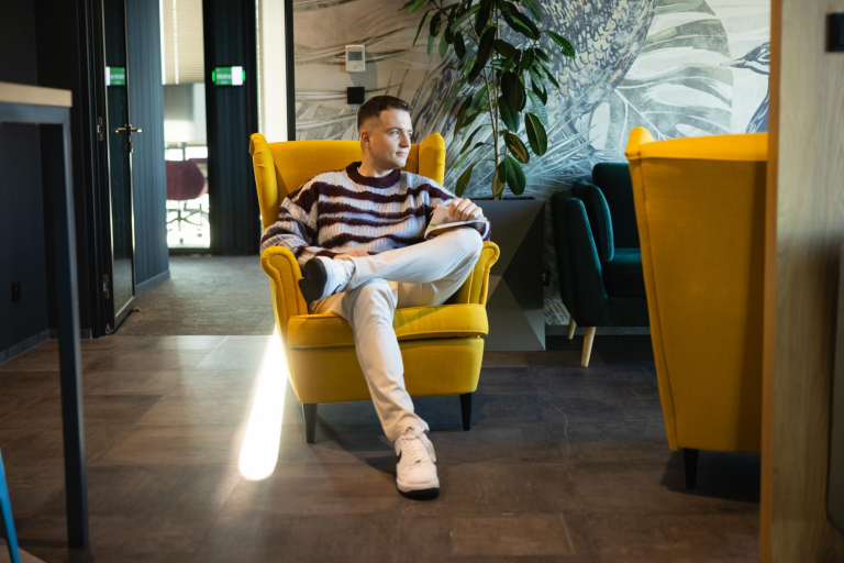 Library | WSB Merito Warsaw University: Student siedzi na żółtym fotelu 