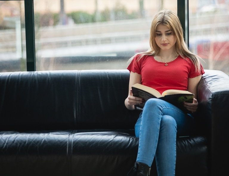 Project management, studia II stopnia, magisterskie: studentka siedząca na kanapie i czytająca książkę