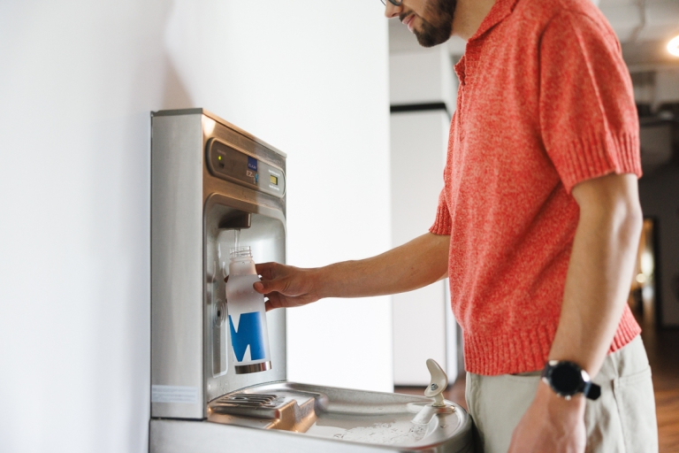 Our campus | WSB Merito Wrocław University: student napełniający butelkę przy źródełku wody pitnej