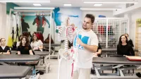 Fizjoterapia sportowa | Studia podyplomowe w Gdańsku | Uniwersytet WSB Merito w Gdańsku: Wykładowca podczas zajęć z fizjoterapii pokazuje coś na szkielecie