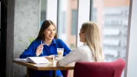 Pedagogika opiekuńczo-wychowawcza z proﬁlaktyką społeczną | Studia II stopnia ze studiami podyplomowymi  | Uniwersytet WSB Merito w Gdańsku: Studentki podczas rozmowy przy stoliku w kawiarni 