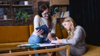 Przygotowanie pedagogiczne | Studia podyplomowe w Gdańsku | Uniwersytet WSB Merito w Gdańsku: Kobieta pomaga dziewczynce przy odrabianiu pracy domowej