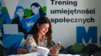 Smart Governance - Nowoczesna Administracja i Cyfrowe Społeczeństwo | Studia I stopnia w Gdańsku | Uniwersytet WSB Merito w Gdańsku: Studentka przy banerze treningu umiejętności społecznych