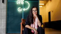 Social media i influencer marketing | Uniwersytet WSB Merito w Gdańsku: Kobieta w dużych okularach siedzi obok neonu