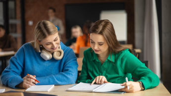 Bezpieczeństwo i przetrwanie w warunkach ekstremalnych | Studia I stopnia w Gdańsku | Uniwersytet WSB Merito w Gdańsku: dwie dziewczyny siedzą przy biurku i pochylają się nad zeszytami