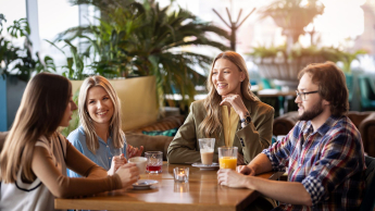 Kontynuuj studia | Uniwersytet WSB Merito w Gdańsku: Grupa studentów w wolnym czasie siedzi przy stoliku w restauracji 