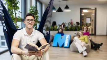 Management | Uniwersytet WSB Merito w Gdańsku: Student siedzi w hamaku i w rękach trzyma książkę, a za nim siedzą studentki