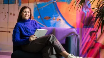 Narzędzia AI w biznesie | Studia I stopnia w Gdańsku | Uniwersytet WSB Merito w Gdańsku: Studentka siedzi w fotelu z tabletem w kolorowej strefie studenta