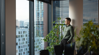 Administrowanie nieruchomościami | Studia I stopnia w Gdańsku | Uniwersytet WSB Merito w Gdańsku: Zdjęcie mężczyzny patrzącego przez dużą szybę na budynki