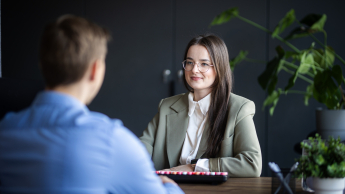 Zarządzanie zasobami ludzkimi | Studia I stopnia w Gdańsku | Uniwersytet WSB Merito w Gdańsku: Zdjęcie z rozmowy pomiędzy kobietą a mężczyzną przy biurku