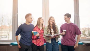 Analityk biznesowy | Studia II stopnia ze studiami podyplomowymi  | Uniwersytet WSB Merito w Gdańsku: Zdjęcie studentów przy parapecie. Dziewczyny są umieszczone w środku, panowie po bokach. Na zdjęciu jest dużo słońca