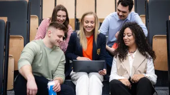 International business | Uniwersytet WSB Merito w Gdańsku: Studenci siedzą na auli w grupie przy laptopie