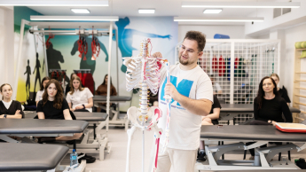 Fizjoterapia sportowa | Studia podyplomowe w Gdańsku | Uniwersytet WSB Merito w Gdańsku: Wykładowca podczas zajęć z fizjoterapii pokazuje coś na szkielecie