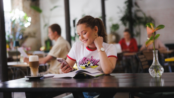 Psychodietetyka | Studia I stopnia w Gdańsku | Uniwersytet WSB Merito w Gdańsku: Studentka w przestrzeni kawiarni przy książce 