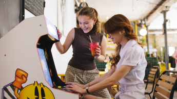 Interaktywna grafika cyfrowa | Studia I stopnia w Gdańsku | Uniwersytet WSB Merito w Gdańsku: Studentki przy starym automacie do gier