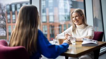 Efektywność energetyczna, odnawialne źródła energii i inne narzędzia prowadzące do transformacji energetycznej | Uniwersytet WSB Merito w Gdańsku: Studentki rozmawiają podczas wizyty w kawiarni. Siedzą przy stoliku przy kawie