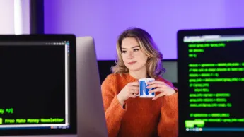 Computer Programming | Uniwersytet WSB Merito w Gdańsku: Studentka przy monitorach i z kubkiem w ręku