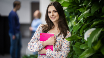 Psychologia zdrowia | Studia jednolite magisterskie w Gdańsku | Uniwersytet WSB Merito w Gdańsku: Studentka przy zielonej ścianie z książką w ręku