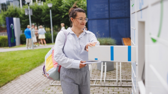 Zarządzanie nieruchomościami i pośrednictwo | Studia I stopnia w Gdańsku | Uniwersytet WSB Merito w Gdańsku: Studentka wkładająca książkę do książkomatu