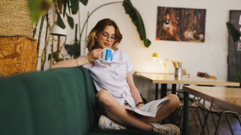 FinTech i Big Data | Studia II stopnia ze studiami podyplomowymi  | Uniwersytet WSB Merito w Gdańsku: Studentka siedząca w kawiarni z brandowym kubkiem Uniwersytetu w ręku 