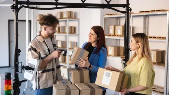 Lean w cyfrowych łańcuchach dostaw | Uniwersytet WSB Merito w Gdańsku: Studenci kierunku logistyka w magazynie z kartonami