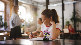 Zarządzanie sprzedażą i nowe media w turystyce | Studia II stopnia ze studiami podyplomowymi  | Uniwersytet WSB Merito w Gdańsku: Zdjęcie studentki w kawiarni robiącej notatki 