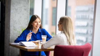 Pedagogika opiekuńczo-wychowawcza z proﬁlaktyką społeczną | Studia II stopnia ze studiami podyplomowymi  | Uniwersytet WSB Merito w Gdańsku: Studentki podczas rozmowy przy stoliku w kawiarni 