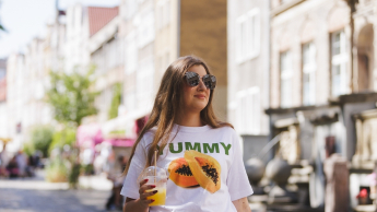 Menedżer turystyki i hotelarstwa | Studia II stopnia ze studiami podyplomowymi  | Uniwersytet WSB Merito w Gdańsku: Studentka z napojem na ulicy św. Ducha