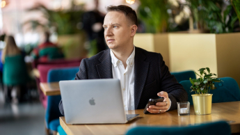 Zarządzanie zasobami ludzkimi | Studia II stopnia ze studiami podyplomowymi  | Uniwersytet WSB Merito w Gdańsku: Student w kawiarni z laptopem i komórką w ręku