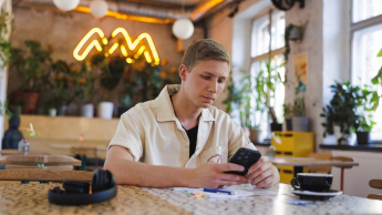 Programowanie | Uniwersytet WSB Merito w Gdańsku: Student przy telefonie w kawiarni 