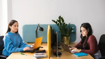 Studentki przy biurku przy laptopach podczas pracy