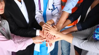 Lider zarządzania doświadczeniami pacjenta i transformacji systemu ochrony zdrowia | Studia podyplomowe w Gdańsku | Uniwersytet WSB Merito w Gdańsku: Ludzie w geście solidarności, jedna z osób ma na sobie fartuch