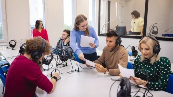 Filologia angielska z językiem norweskim | Studia I stopnia w Gdańsku | Uniwersytet WSB Merito w Gdańsku: Studenci podczas warsztatów na filologii. Siedzą oni przy stołach ze słuchawkami