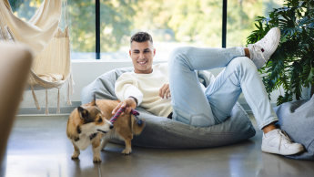 Zarządzanie projektami i Agile w praktyce | Uniwersytet WSB Merito w Gdańsku: Student leży na puffie i bawi się z pieskiem