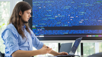 Bezpieczeństwo systemów informatycznych | Studia I stopnia w Gdańsku | Uniwersytet WSB Merito w Gdańsku: Student programista przy laptopie i dużym ekranie