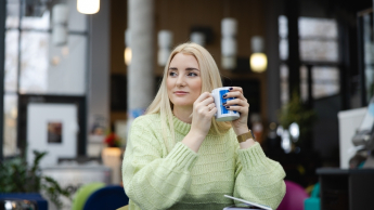 HR Tech. Kompetencje Miękkie w Erze AI | Studia podyplomowe w Gdańsku | Uniwersytet WSB Merito w Gdańsku: Kobieta siedzi z kubkiem w dłoni