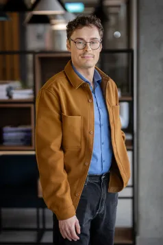 Programowanie gier komputerowych | Studia I stopnia w Gdańsku | Uniwersytet WSB Merito w Gdańsku: Zdjęcie biznesowe studenta w ciemnej beżowej kurtce i niebieskiej koszuli