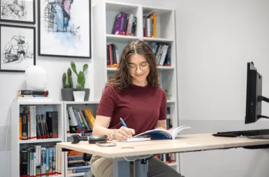 Biblioteka | Uniwersytet WSB Merito w Gdańsku: Studentka w przestrzeni biblioteki z komputerem i biurkiem