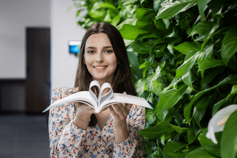 Biblioteka - szkolenie - do ulokalnienia - niepełna | Uniwersytet WSB Merito w Gdańsku: studentka z książką, której strony są zawinięte w serce