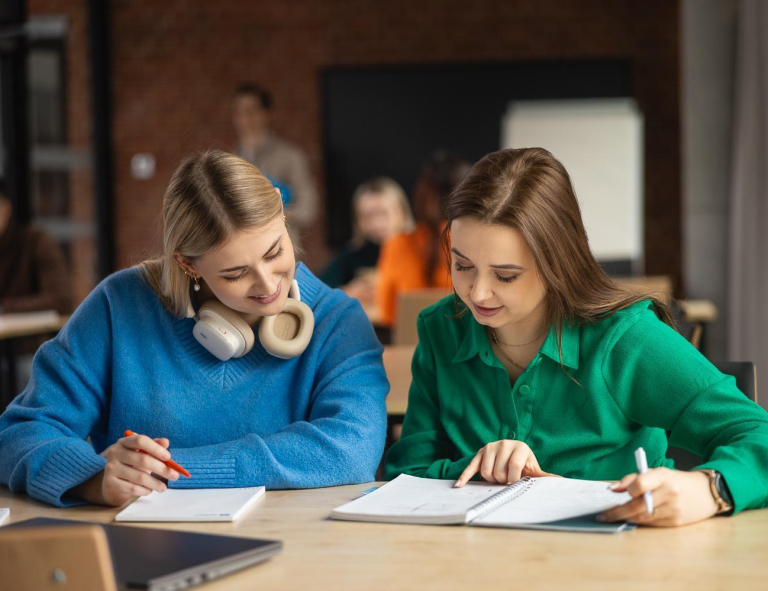 Administrowanie zasobami energetycznymi | Studia II stopnia ze studiami podyplomowymi  | Uniwersytet WSB Merito w Gdańsku: dwie dziewczyny siedzą przy biurku i pochylają się nad zeszytami