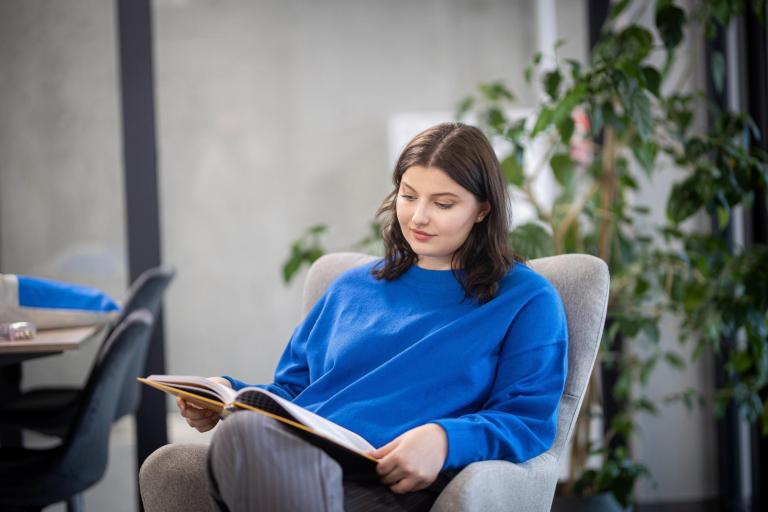 Administracja i biznes | Studia II stopnia w Gdańsku | Uniwersytet WSB Merito w Gdańsku: Studentka w bibliotece z książką 