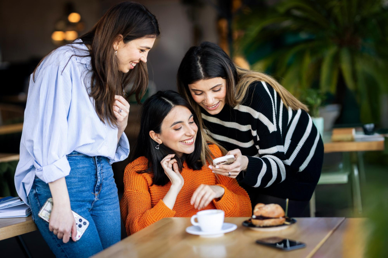 Pedagogika szkoły z integracją imigrantów | Studia I stopnia w Gdańsku | Uniwersytet WSB Merito w Gdańsku: Studentki w kawiarni rozmawiają na temat tego, co widzą w komórce