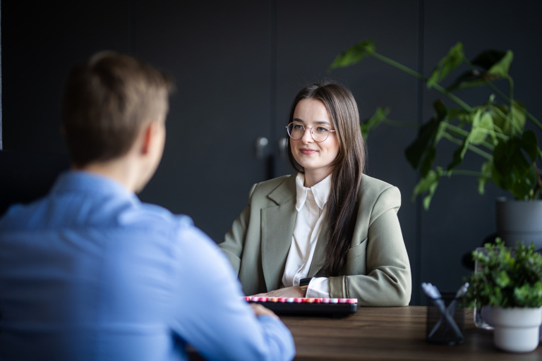 Pedagogika szkoły z integracją imigrantów | Studia II stopnia ze studiami podyplomowymi  | Uniwersytet WSB Merito w Gdańsku: Zdjęcie z rozmowy pomiędzy kobietą a mężczyzną przy biurku