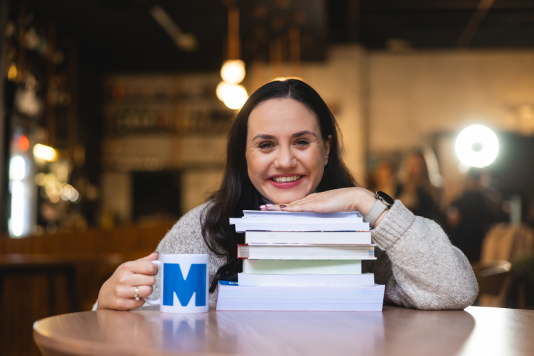 Wyniki wyszukiwania | Uniwersytet WSB Merito w Gdańsku: Portret kobiety, która opiera się brodą o książki, uśmiecha się