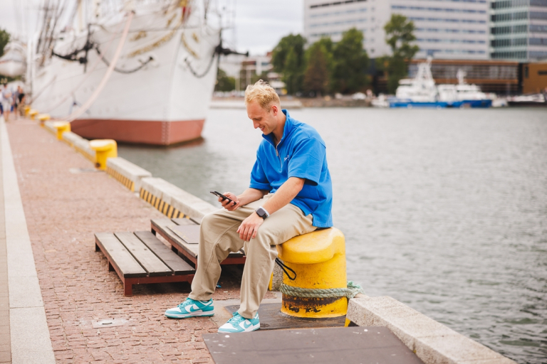Psychokryminalistyka | Studia II stopnia ze studiami podyplomowymi  | Uniwersytet WSB Merito w Gdańsku: Student siedzi na kołku i przegląda komórkę w tle widać statek