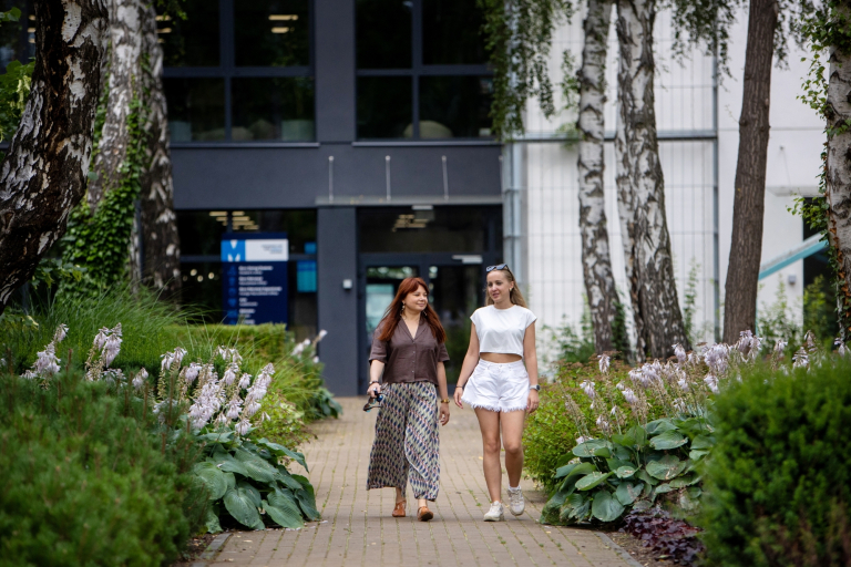 Akademia trenera sportowego | Studia podyplomowe w Gdańsku | Uniwersytet WSB Merito w Gdańsku: Dwie osoby wychodzą z budynku uczelni WSB Merito w Gdansku