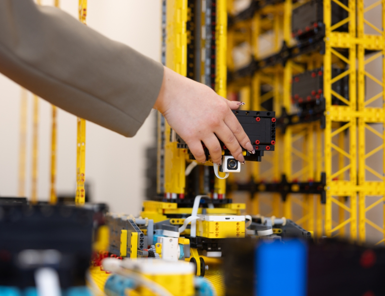 Lean w cyfrowych łańcuchach dostaw | Studia I stopnia w Gdańsku | Uniwersytet WSB Merito w Gdańsku: Ręka studenta przy makiecie