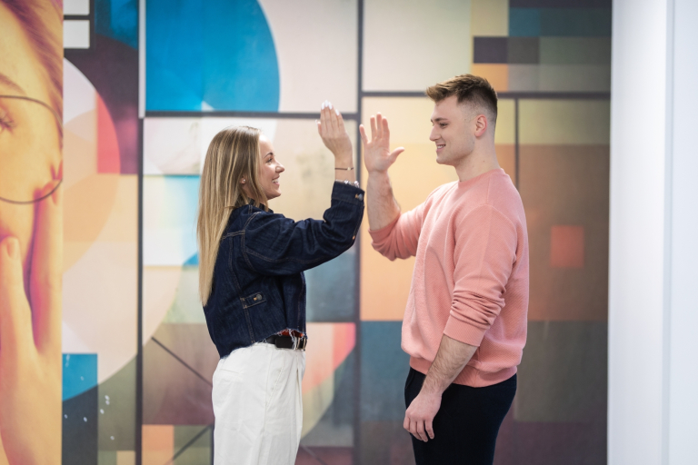 Maturzyści | Uniwersytet WSB Merito w Gdańsku: Studentka i student przybijają sobie piątkę na korytarzu uczelni